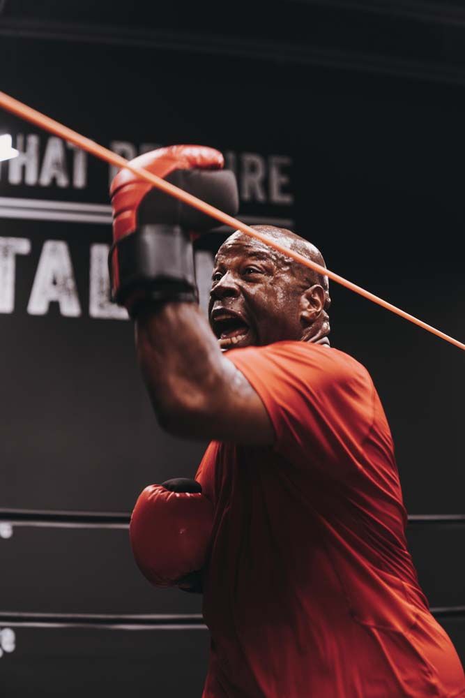 A man wearing boxing gloves is holding a rope in a boxing ring.