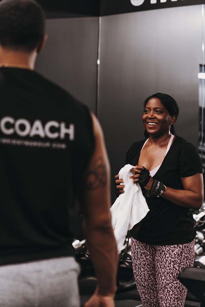 A man and a woman are standing in front of a mirror in a gym.