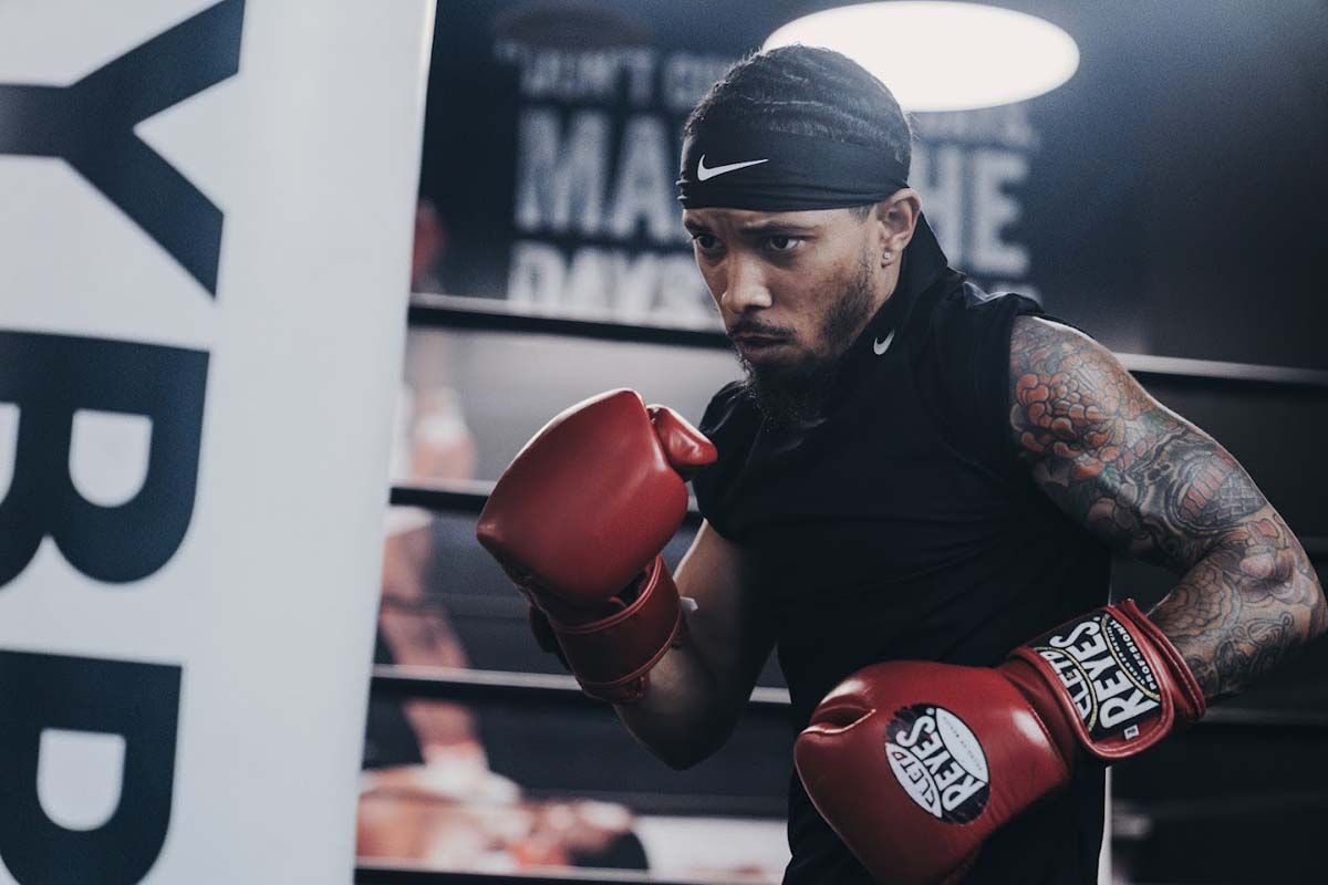 A man wearing red boxing gloves is in a boxing ring
