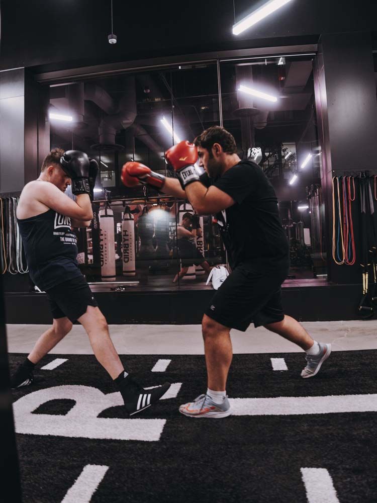 Two men are boxing in a gym in front of a mirror.