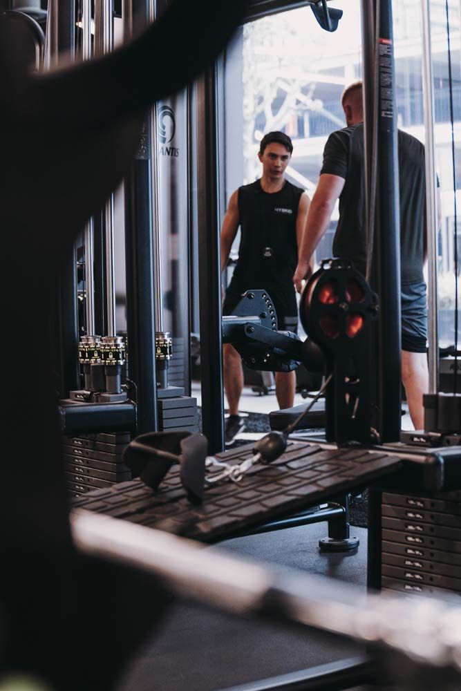 Two men are standing in a gym talking to each other.
