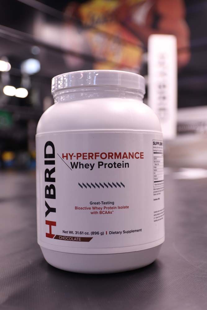 A bottle of hybrid hyper performance whey protein is sitting on a table.