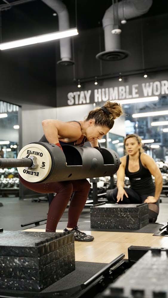 A woman is lifting a barbell in a gym.
