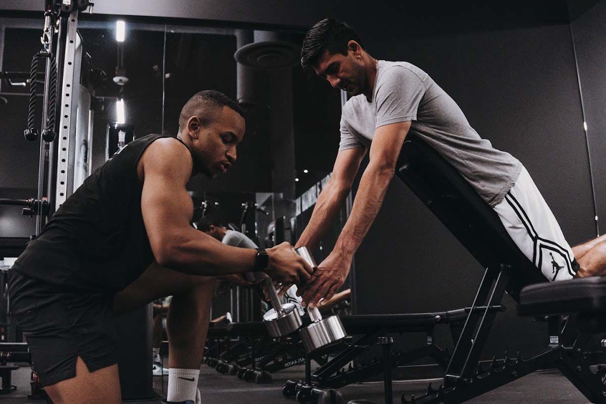 Two men are lifting dumbbells in a gym.