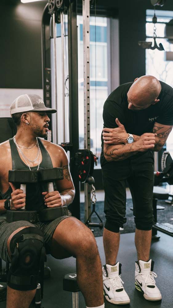 A man is sitting on a bench in a gym holding a dumbbell.