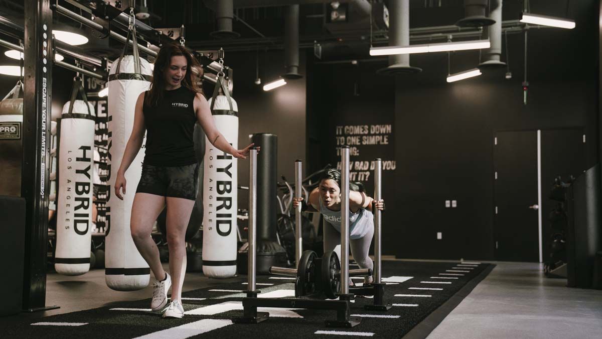 A woman is pushing a sled in a gym.