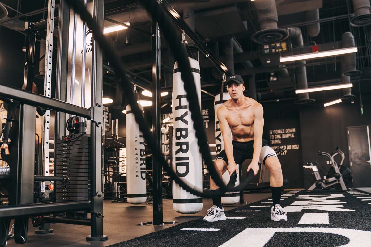 A man is doing exercises with a rope in a gym.
