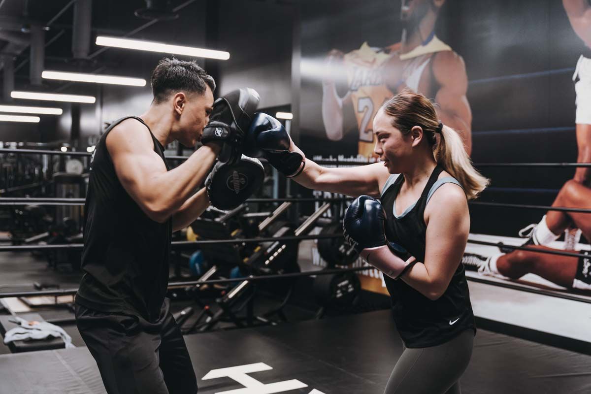A man and a woman are boxing in a gym.