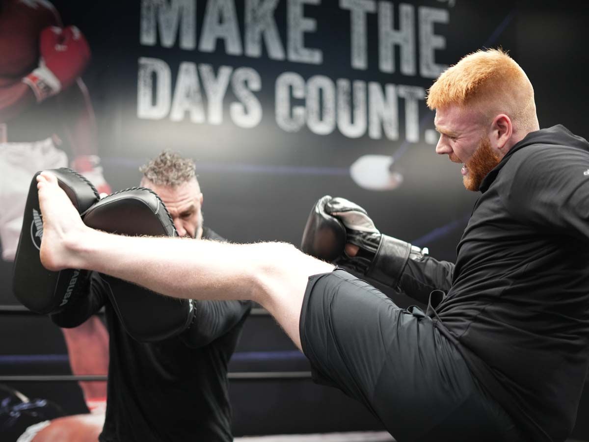 Two men are kickboxing in front of a sign that says make the days count