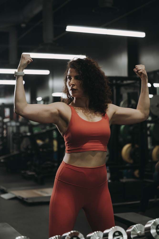 A woman is flexing her muscles in a gym.
