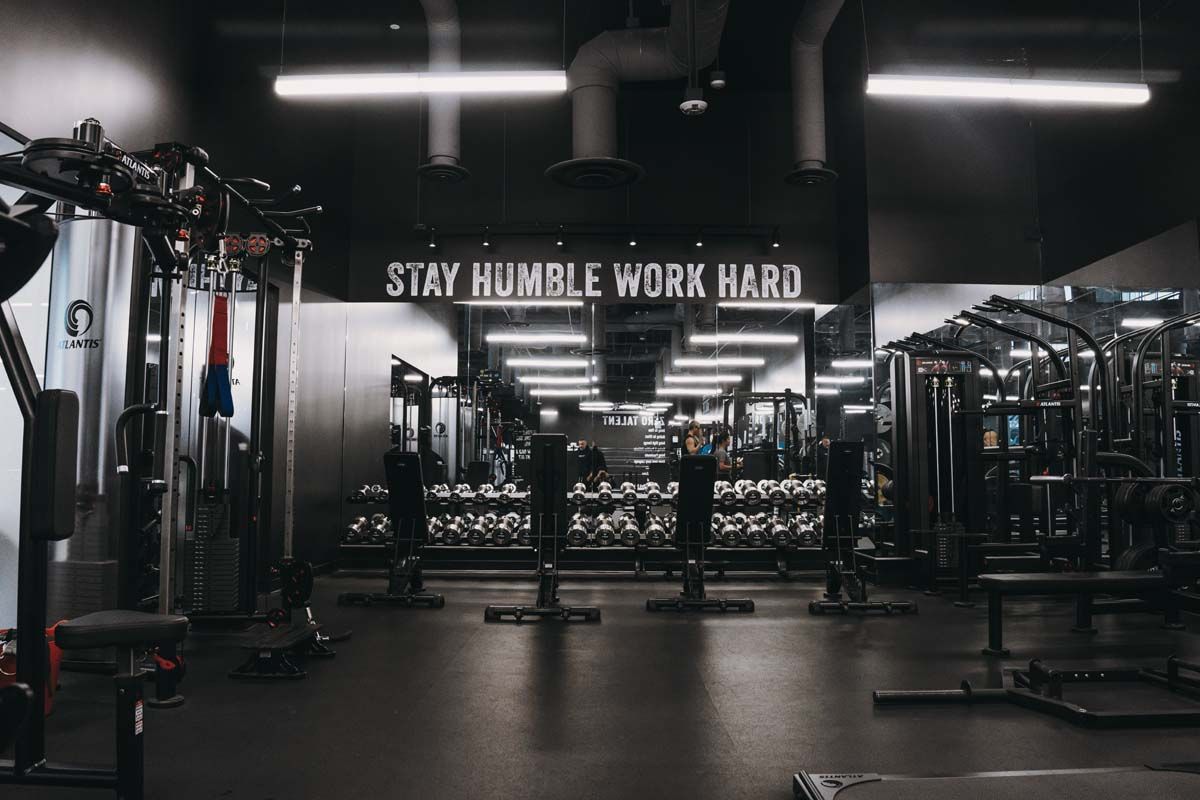 A gym with a sign on the wall that says `` stay humble work hard ''.