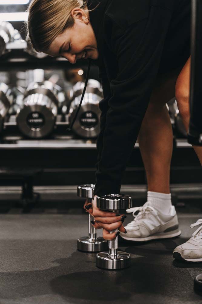 A woman is lifting a dumbbell in a gym.