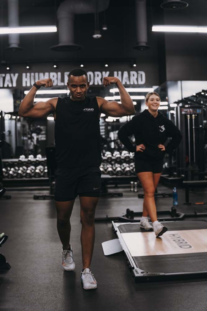 A man and a woman are flexing their muscles in a gym.