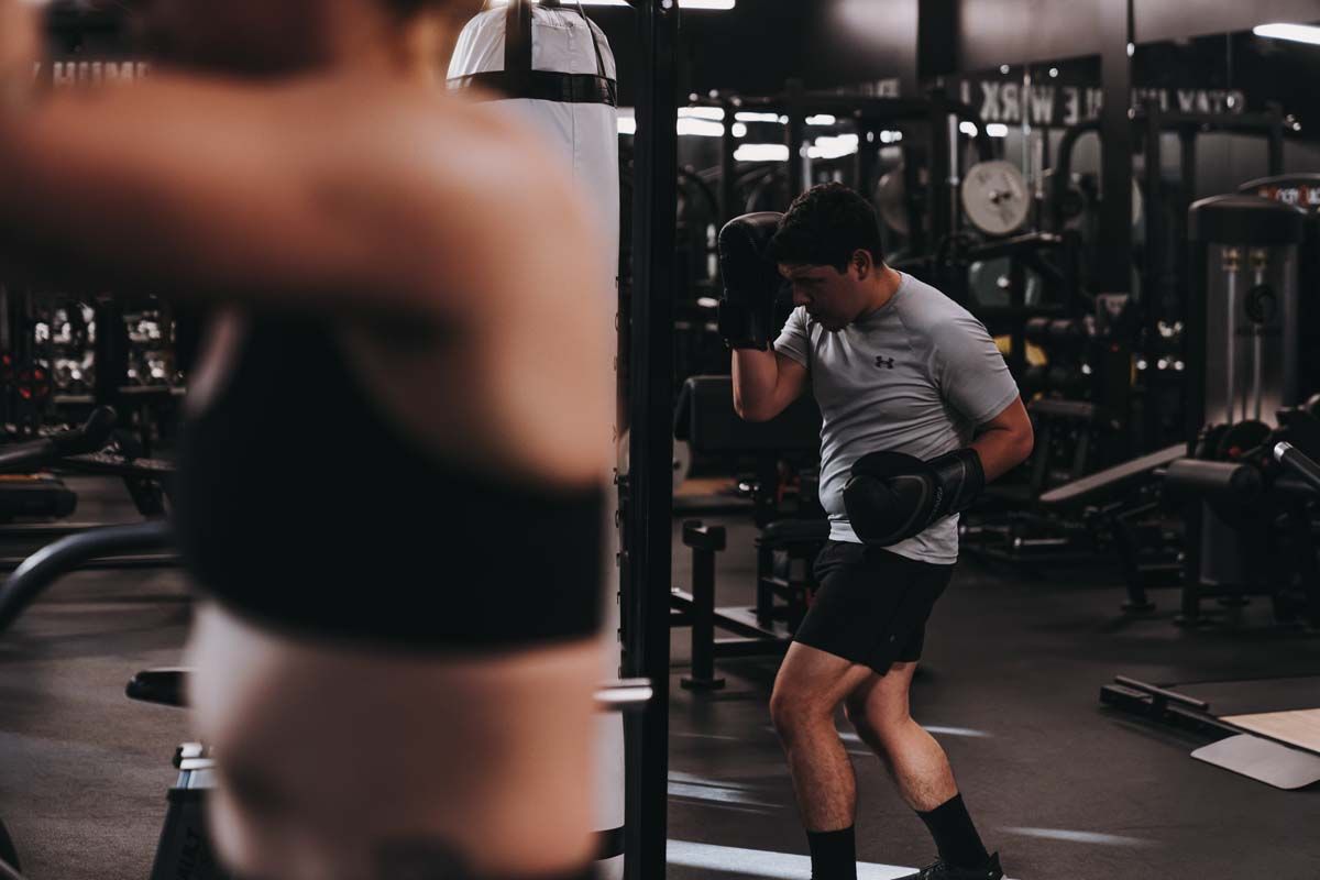 A man and a woman are boxing in a gym.
