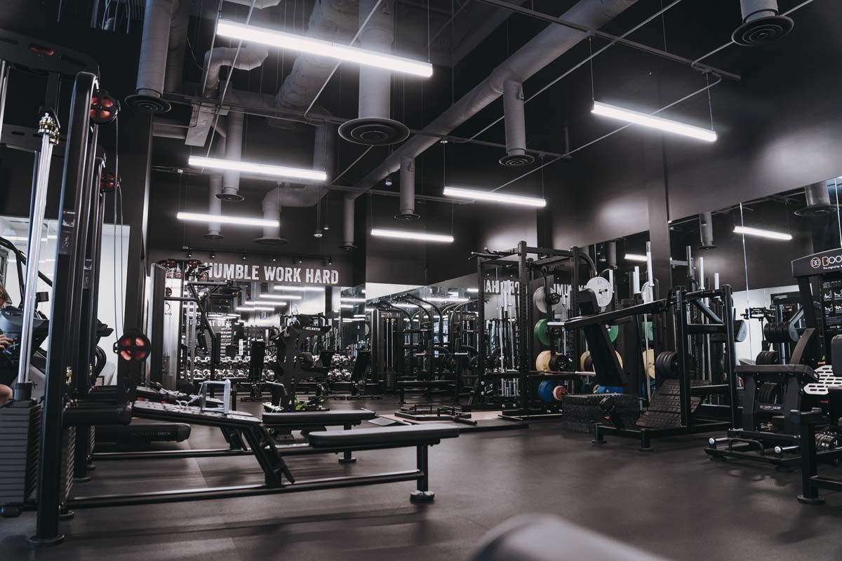 A gym filled with lots of exercise equipment and mirrors.