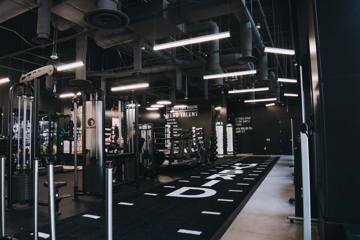 A gym with a lot of exercise equipment and a black mat on the floor.