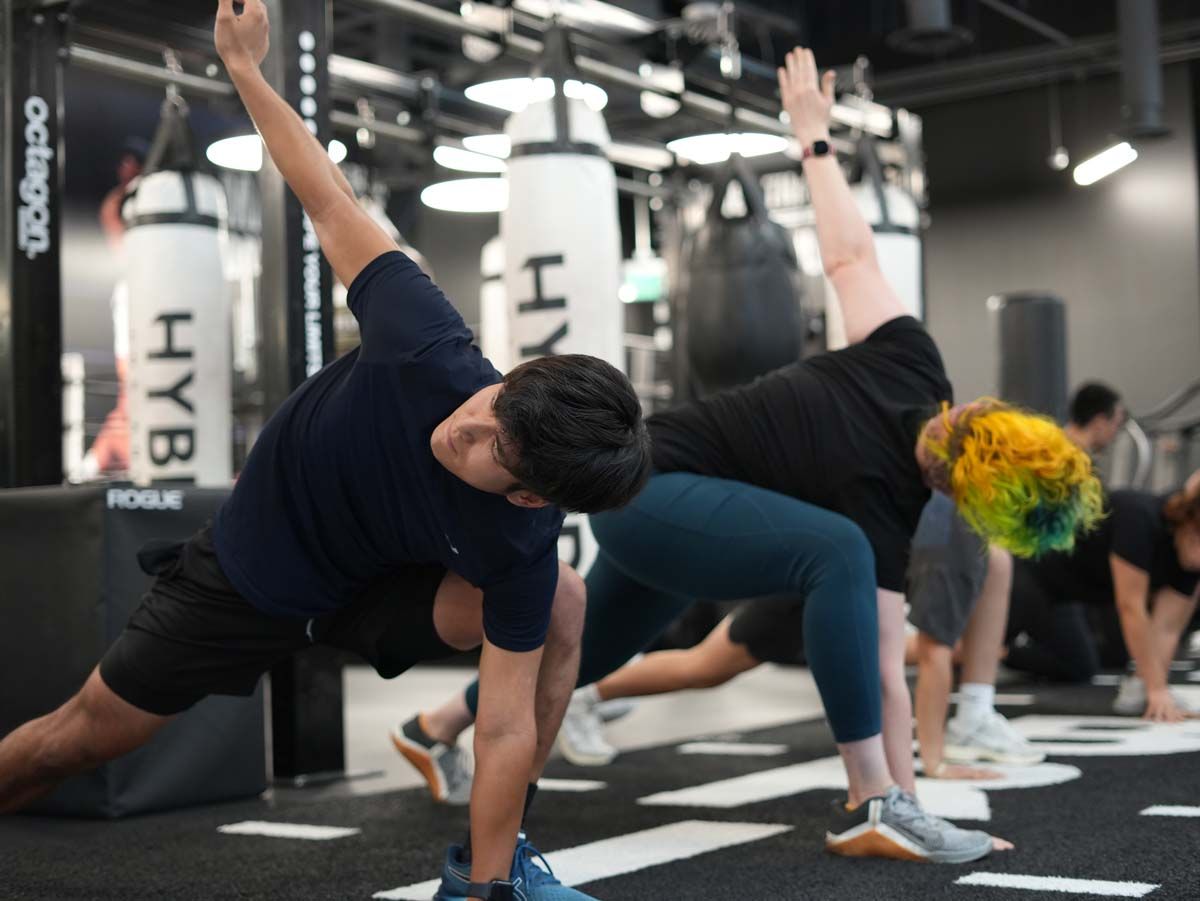 A group of people are doing stretching exercises in a gym
