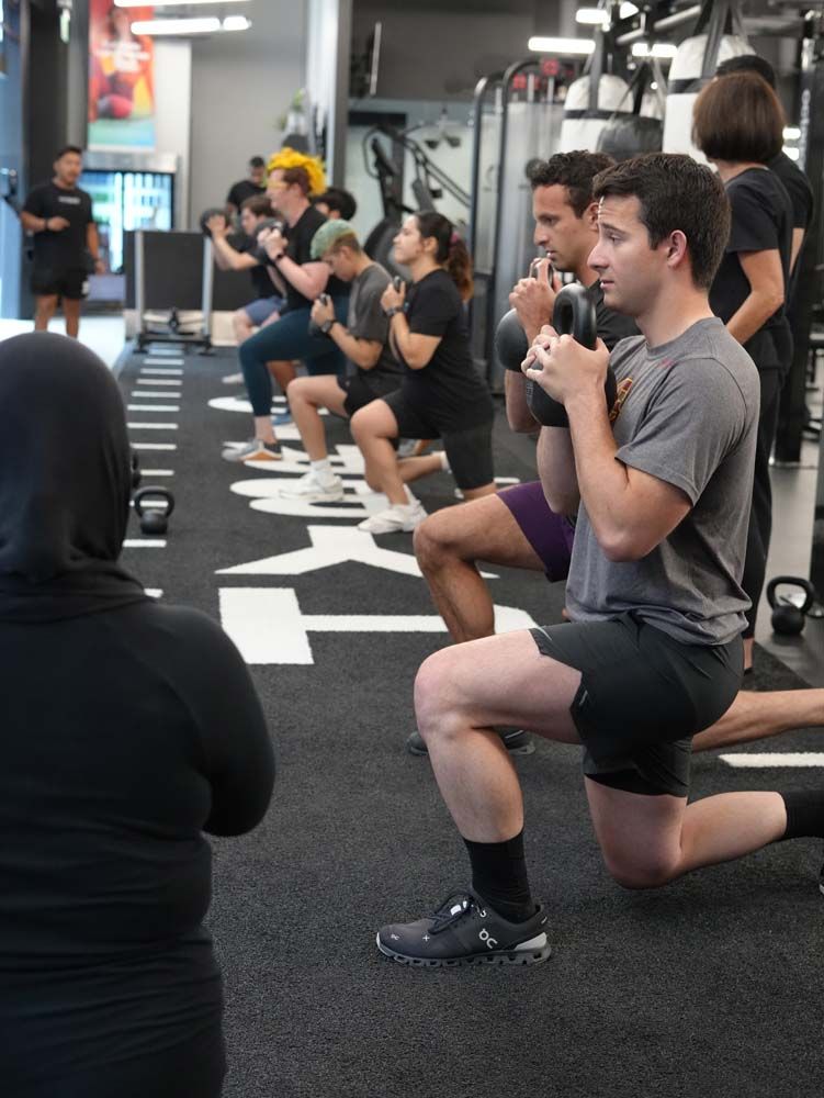 A group of people are doing squats in a gym