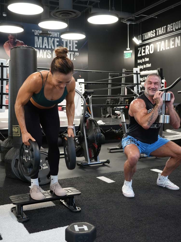 A man and a woman are lifting weights in a gym.