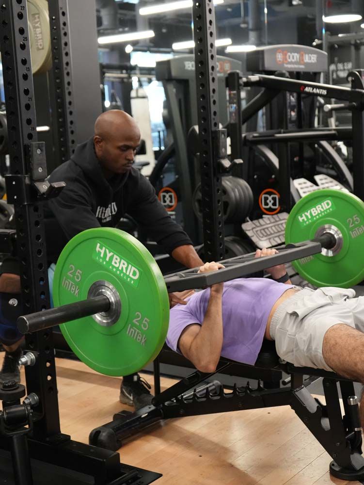 A man is lifting a barbell on a bench in a gym.