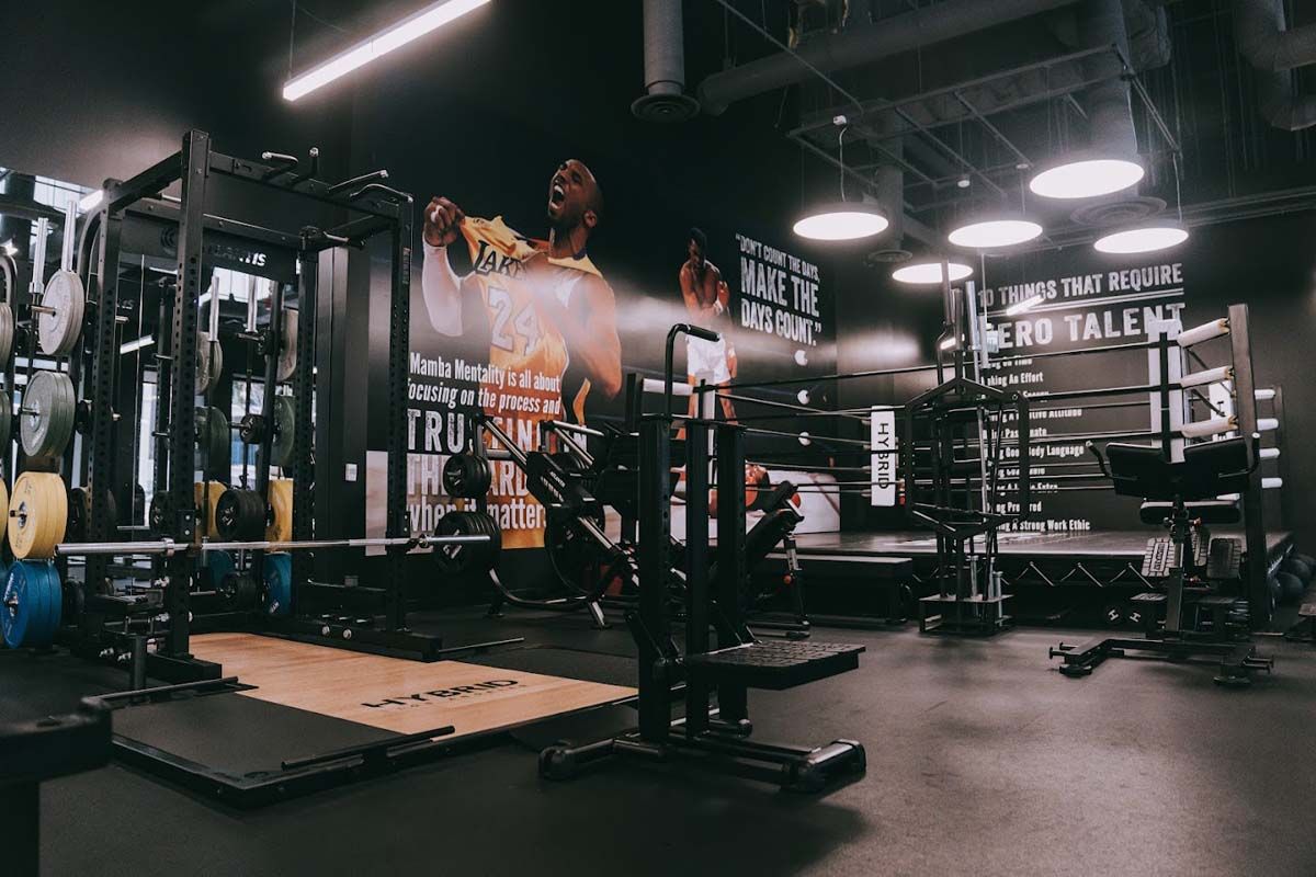 A man is jumping over a barbell in a gym.