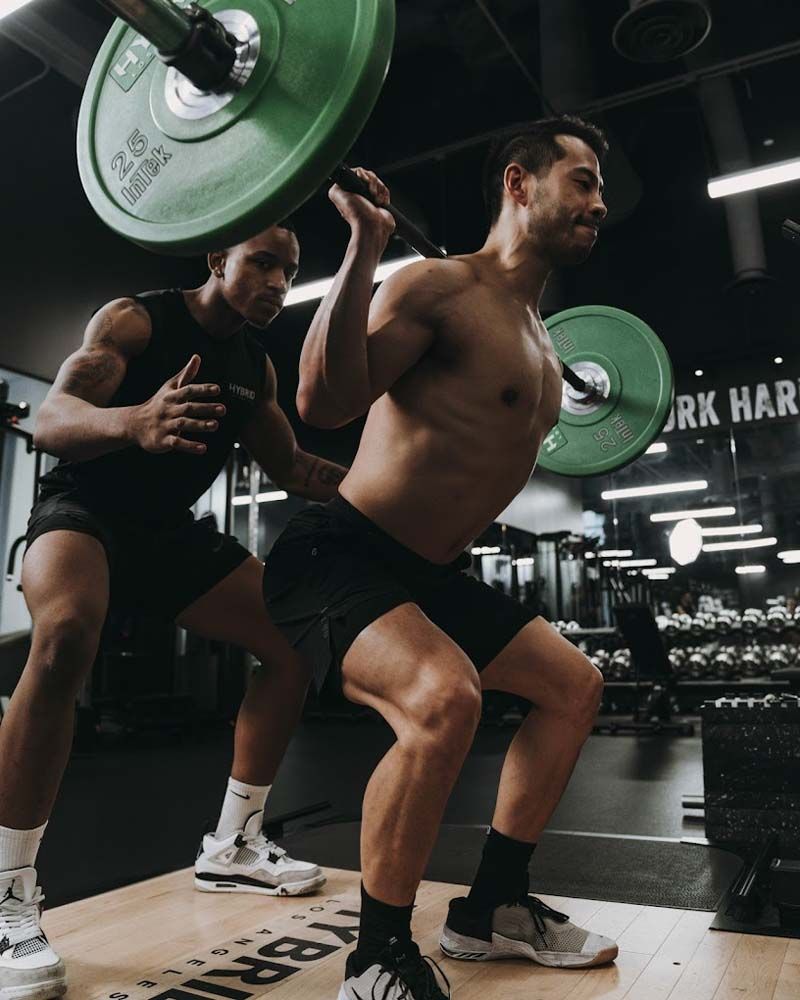 A man squatting with a barbell on his head in a gym
