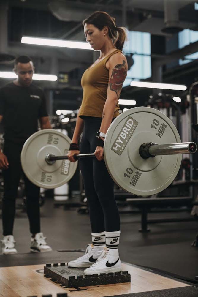 A woman is lifting a barbell in a gym.
