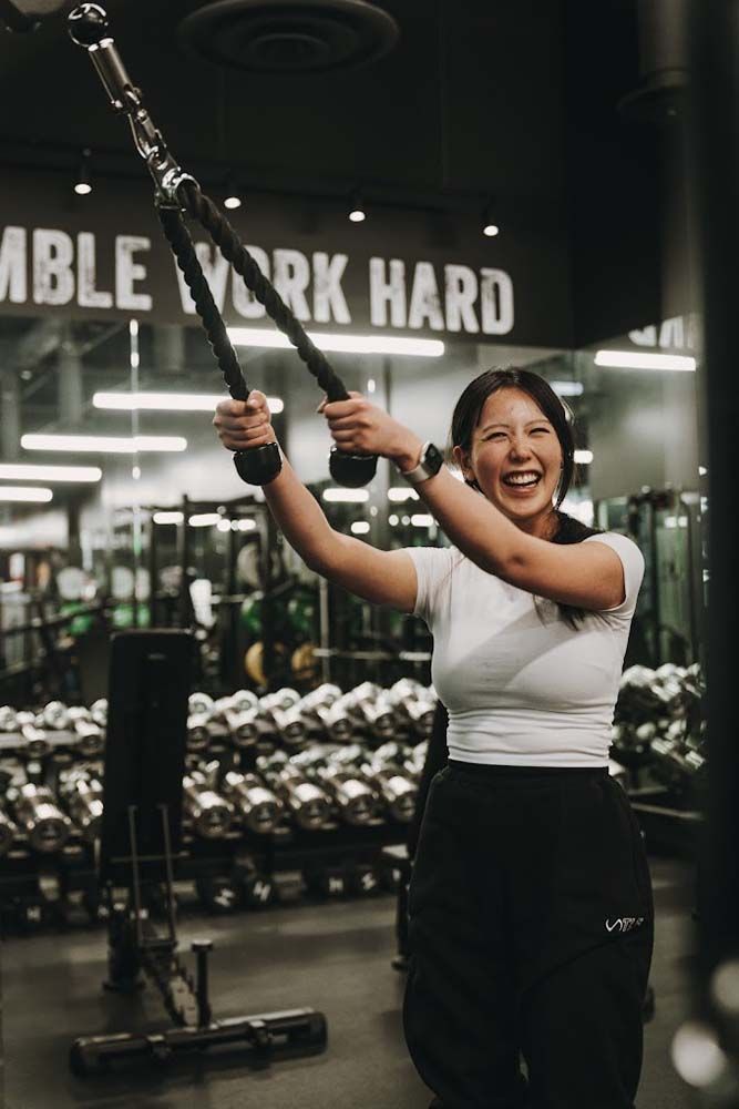 A woman is lifting a barbell in a gym.