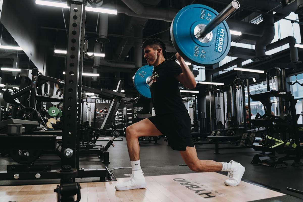 A man is squatting with a barbell in a gym.