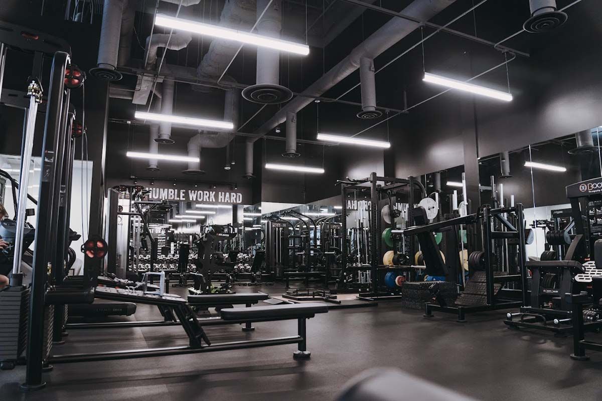 A gym filled with lots of exercise equipment and mirrors.