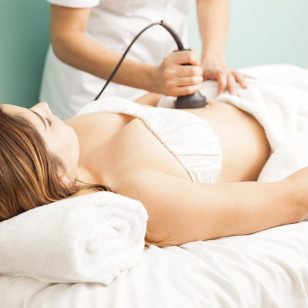 Woman receiving ultrasound therapy on her abdomen while lying down, white setting.