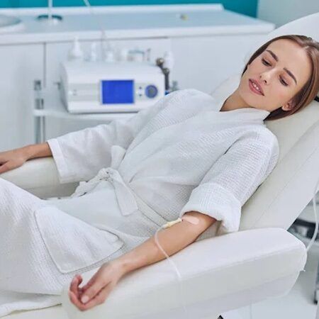 Woman reclines with an IV drip in a medical spa setting.