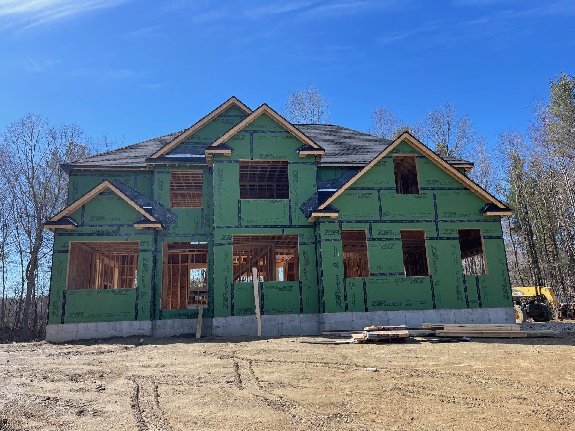 A large house is being built in the middle of a dirt field.