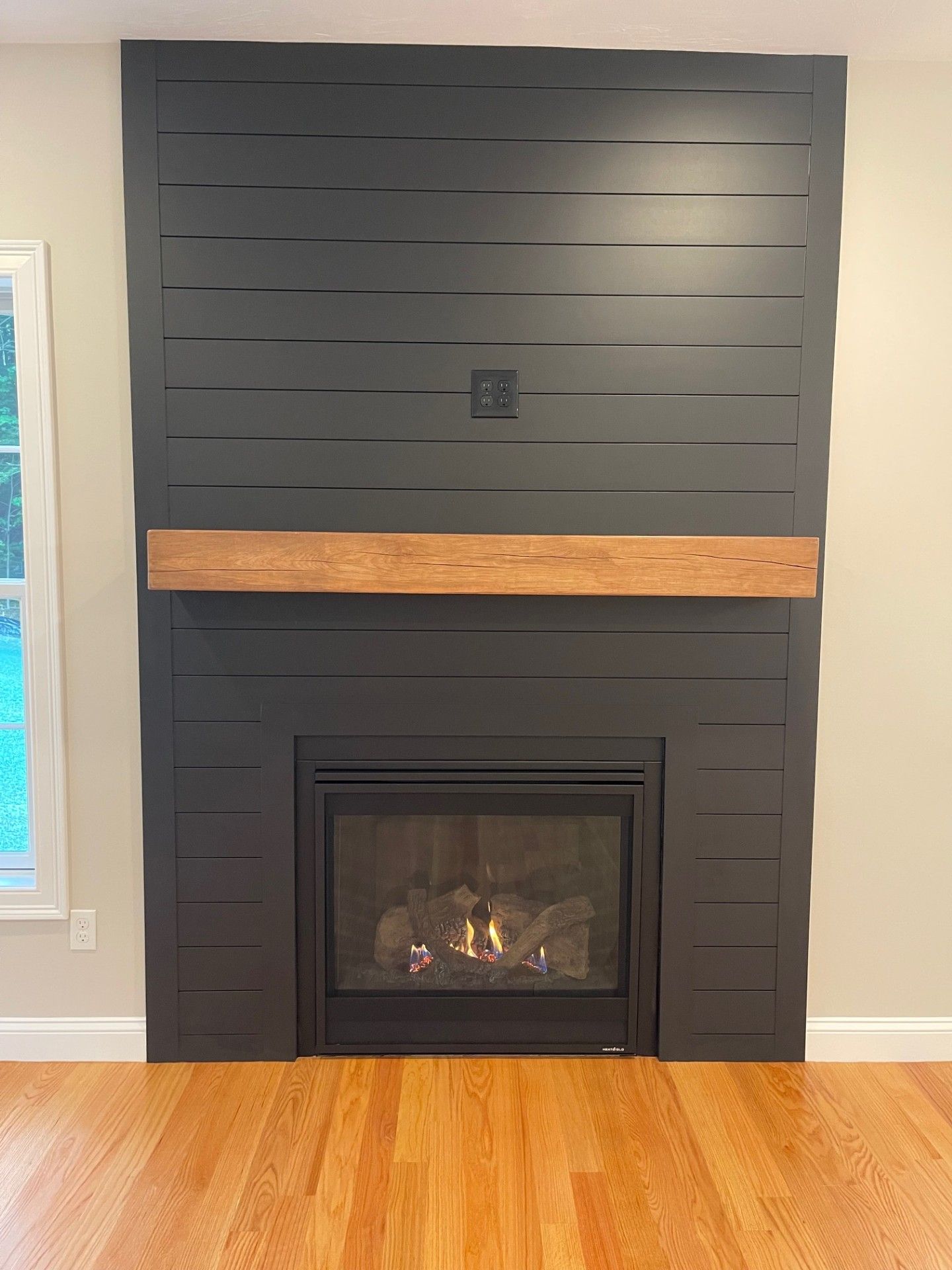 A black fireplace with a wooden mantle in a living room.