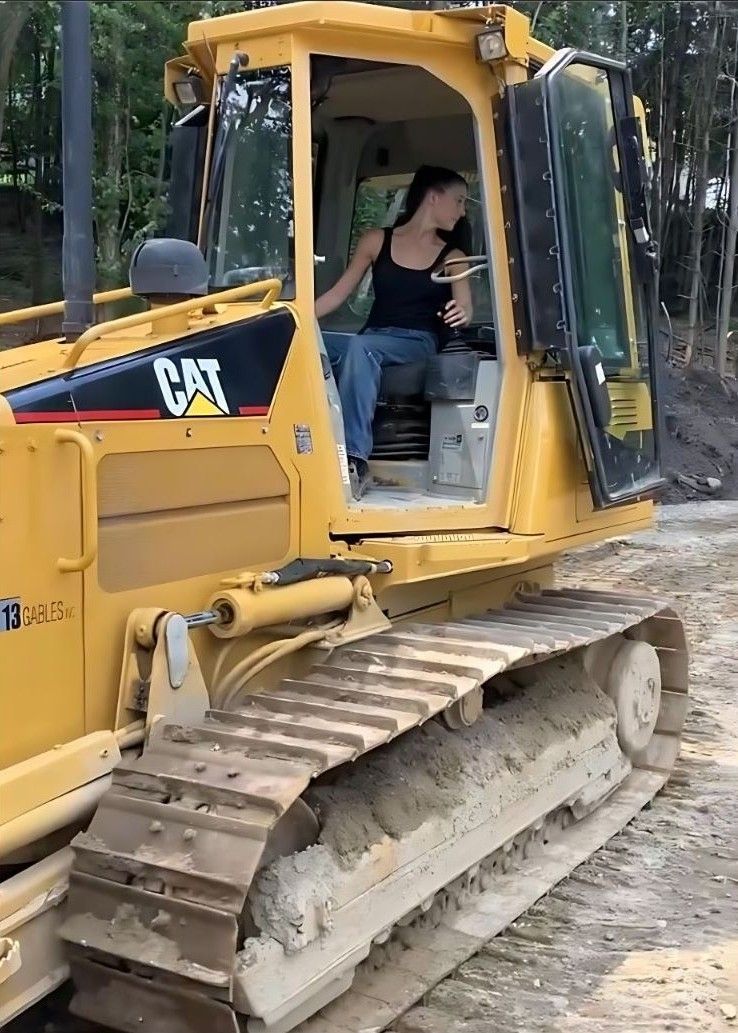A woman is sitting in the cab of a bulldozer.