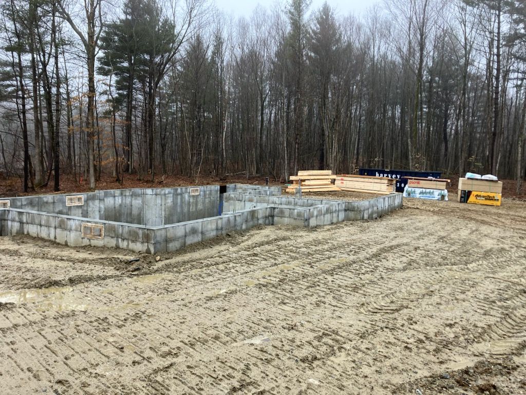 A house is being built in the middle of a dirt field in the woods.