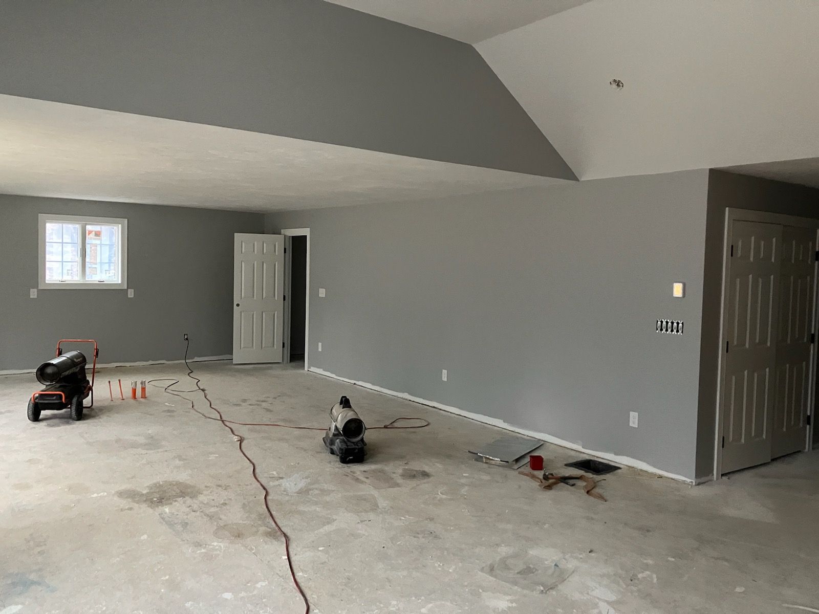 A large empty room with a vaulted ceiling and gray walls.