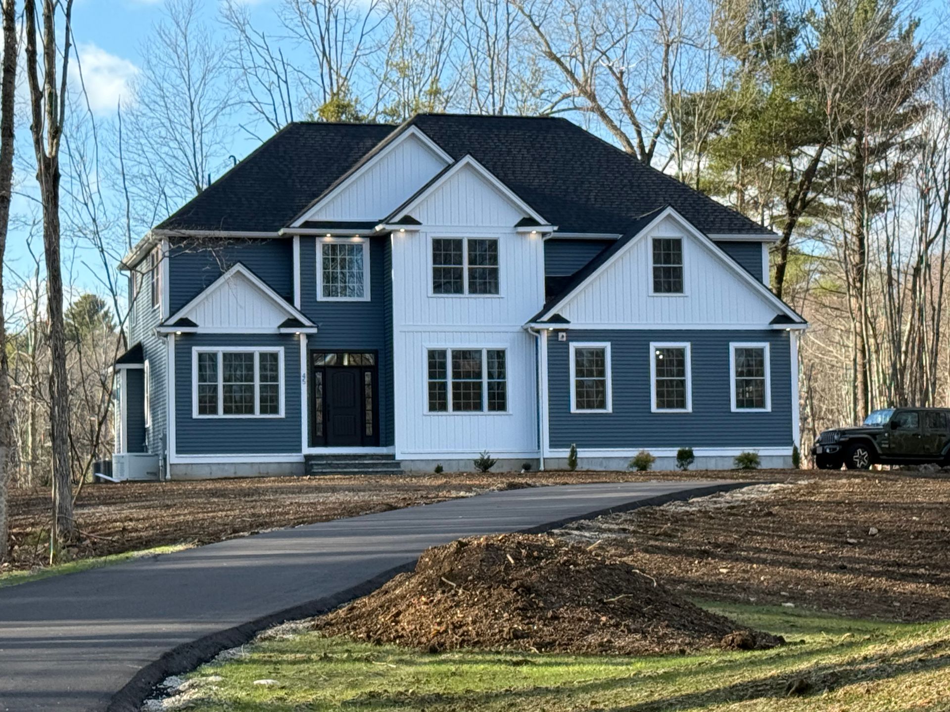 A large blue and white house with a black truck parked in front of it.