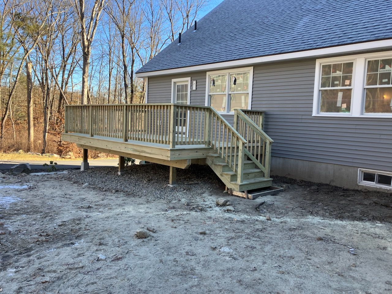 A house with a wooden deck and stairs in front of it.