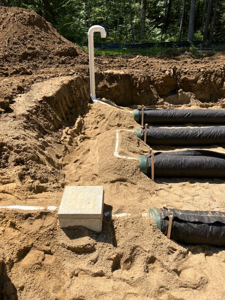 A septic system is being installed in a dirt field.