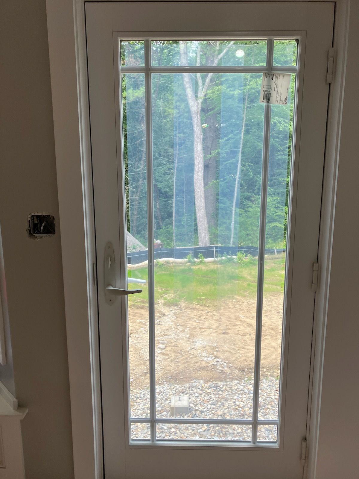 A white door with a view of a forest through it.