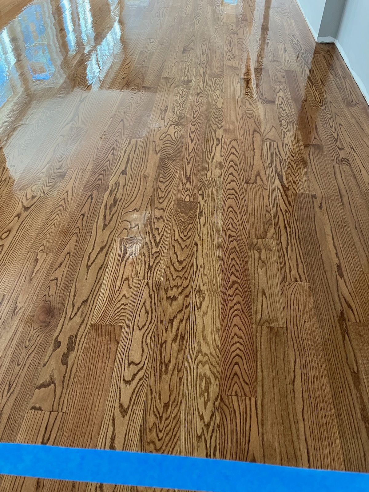 A close up of a wooden floor with a blue tape on it.