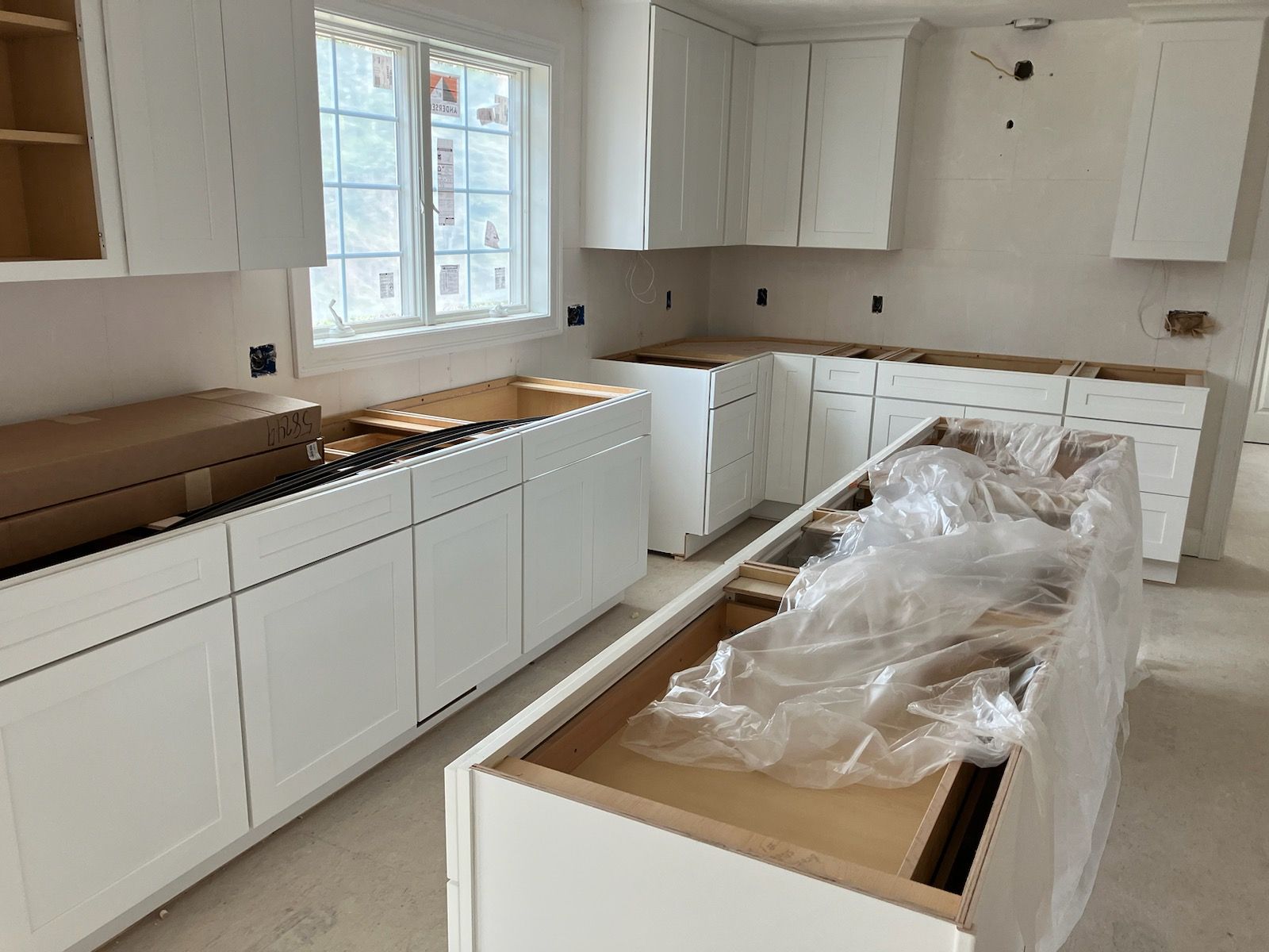 A kitchen under construction with white cabinets and wooden counter tops.