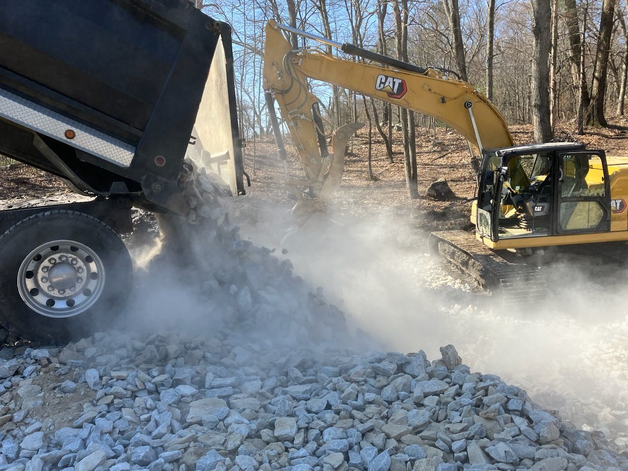 A dump truck is being loaded with rocks by an excavator.