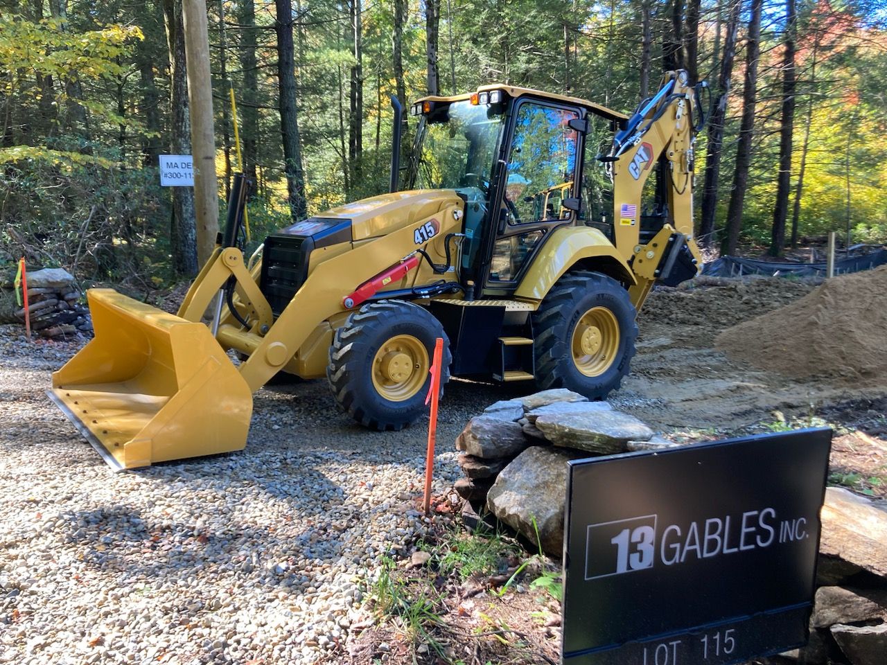 A bulldozer is parked next to a sign that says 13 gables inc.