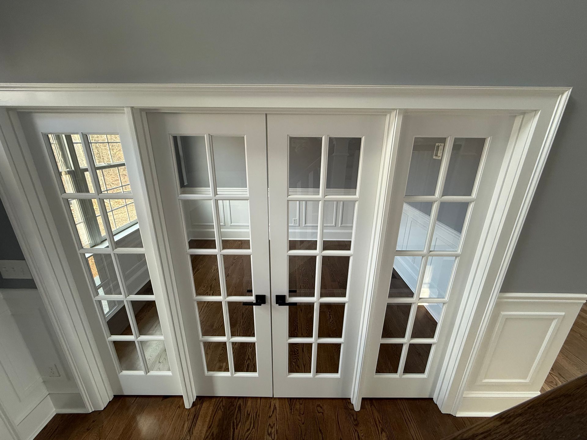 A room with french doors and a wooden floor.