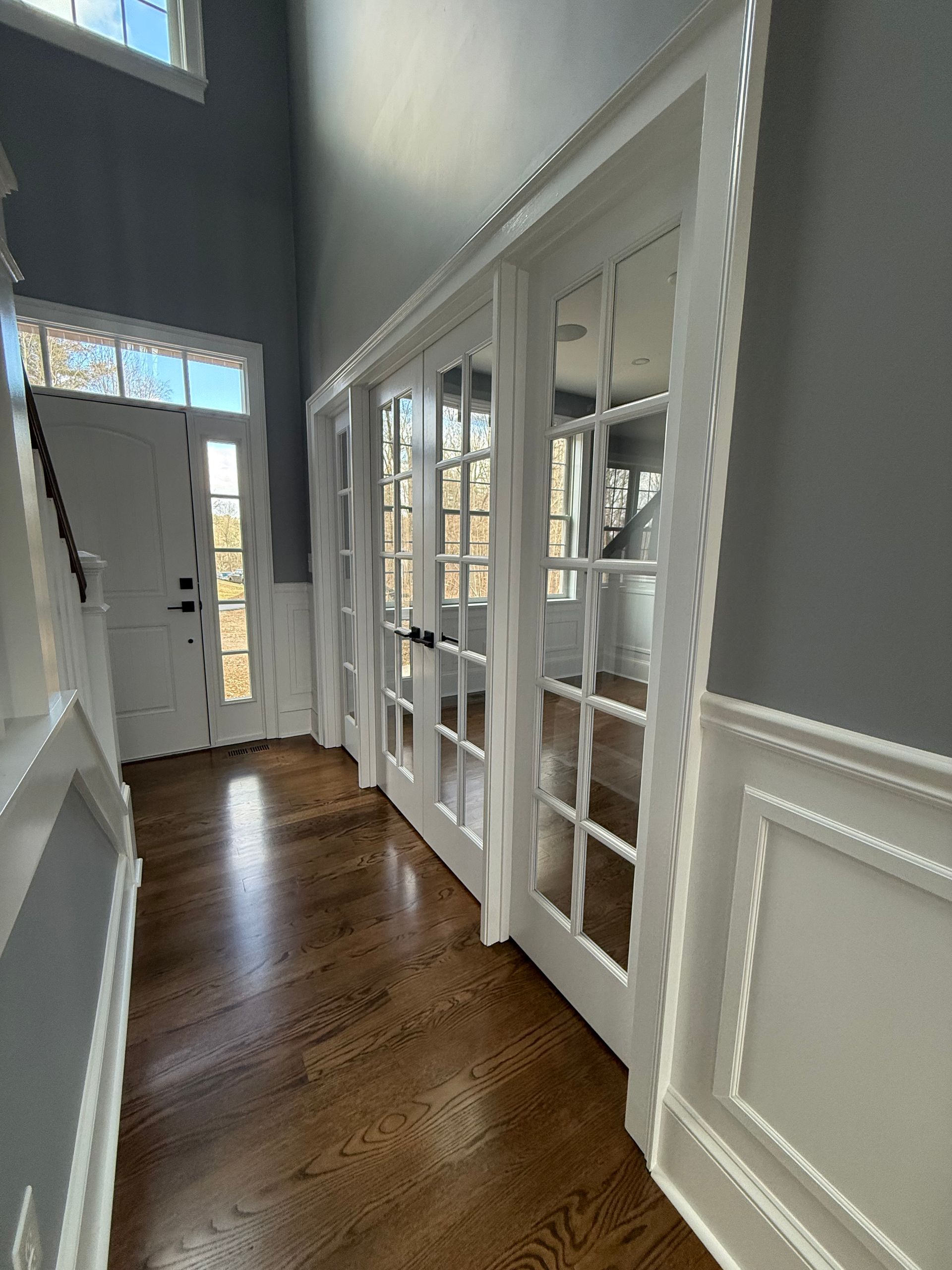 A hallway with hardwood floors and french doors in a house.