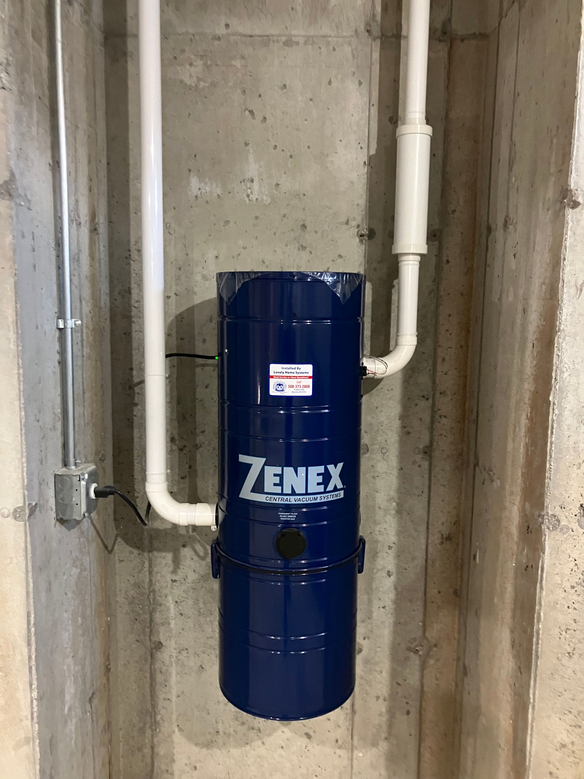 A blue vacuum cleaner is hanging on a concrete wall.