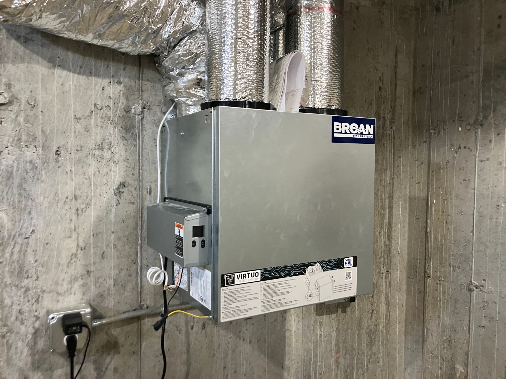 A metal box is hanging on a concrete wall.