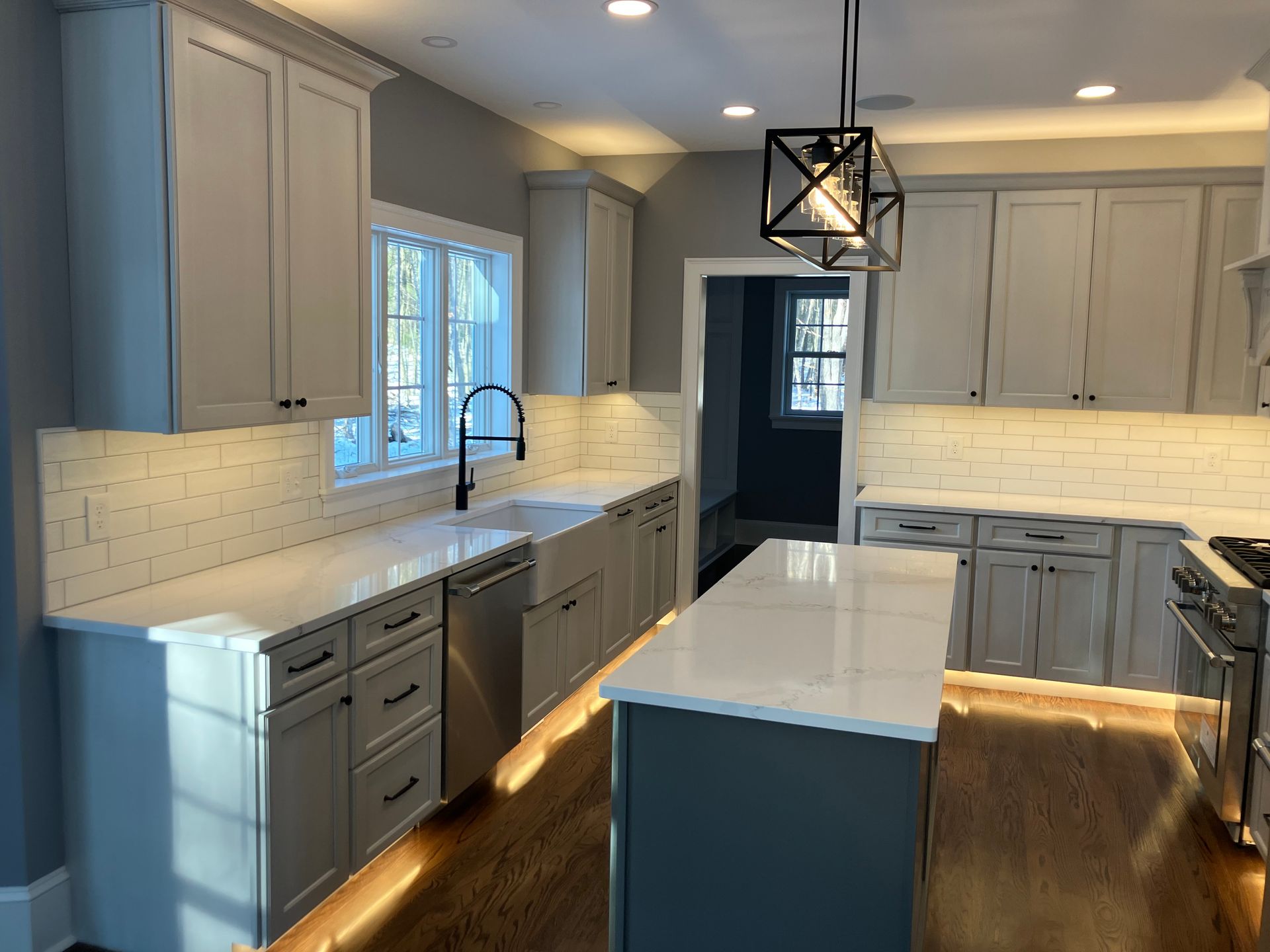 A kitchen with white cabinets , white counter tops , stainless steel appliances , and a large island.